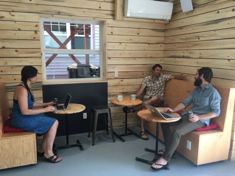 Members chatting and working with laptops in The Coop's wood-paneled lounge area.